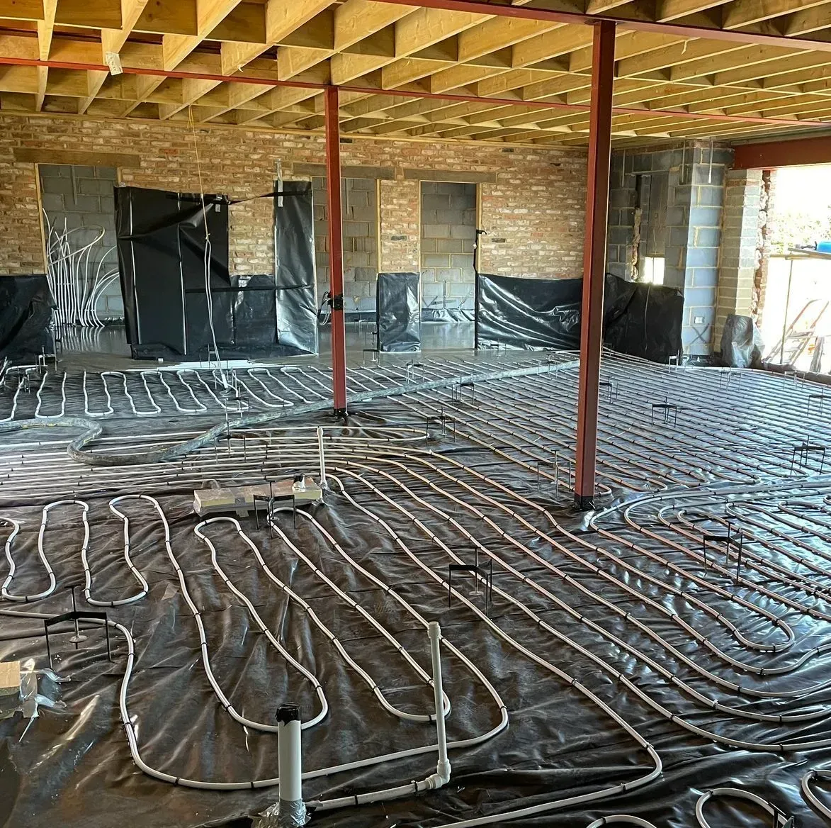 Large room with underfloor heating system pipes, ready to receive a delivery of pumped liquid screed.