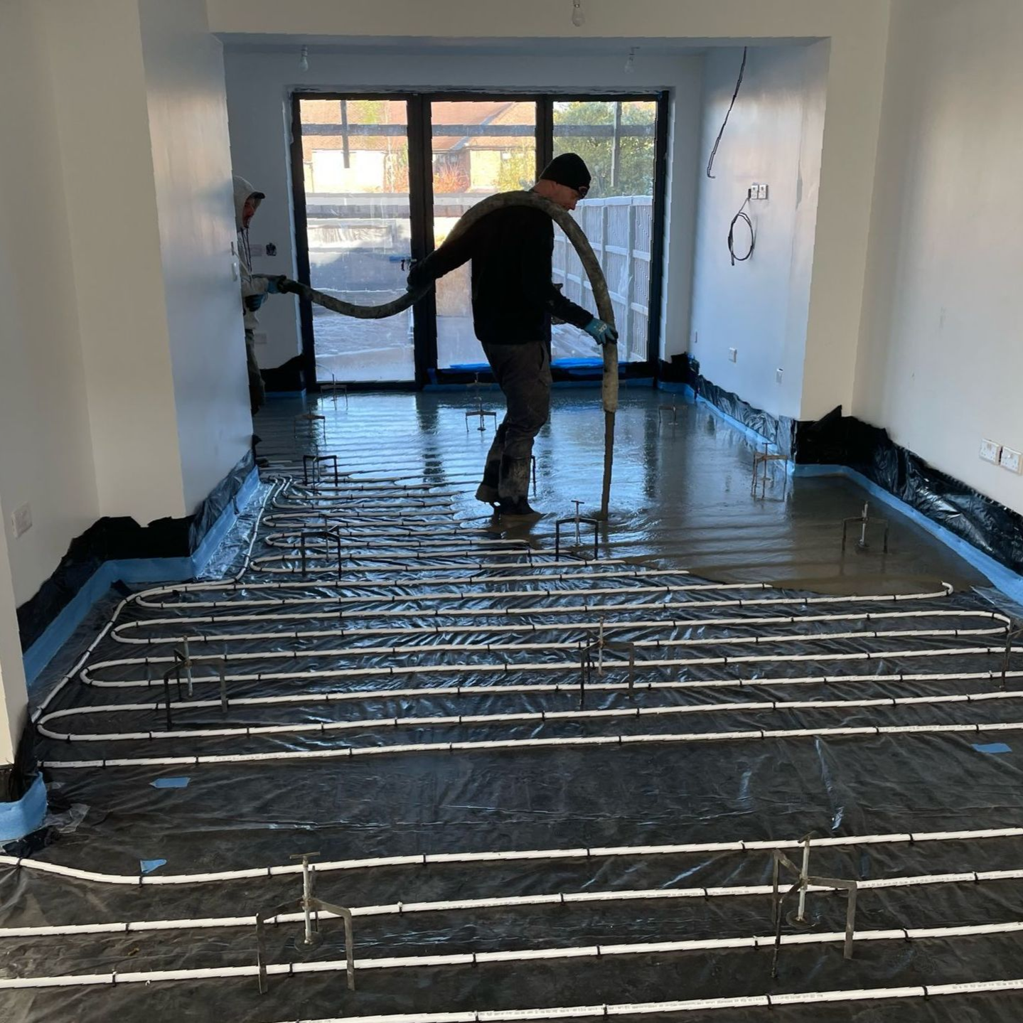 Room with underfloor heating system installed, part way through the liquid screed installation process.