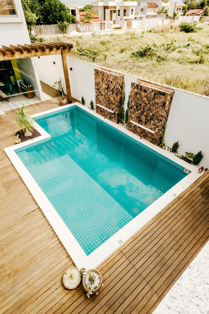 Modern backyard patio with a turquoise swimming pool and wooden deck, seen from above