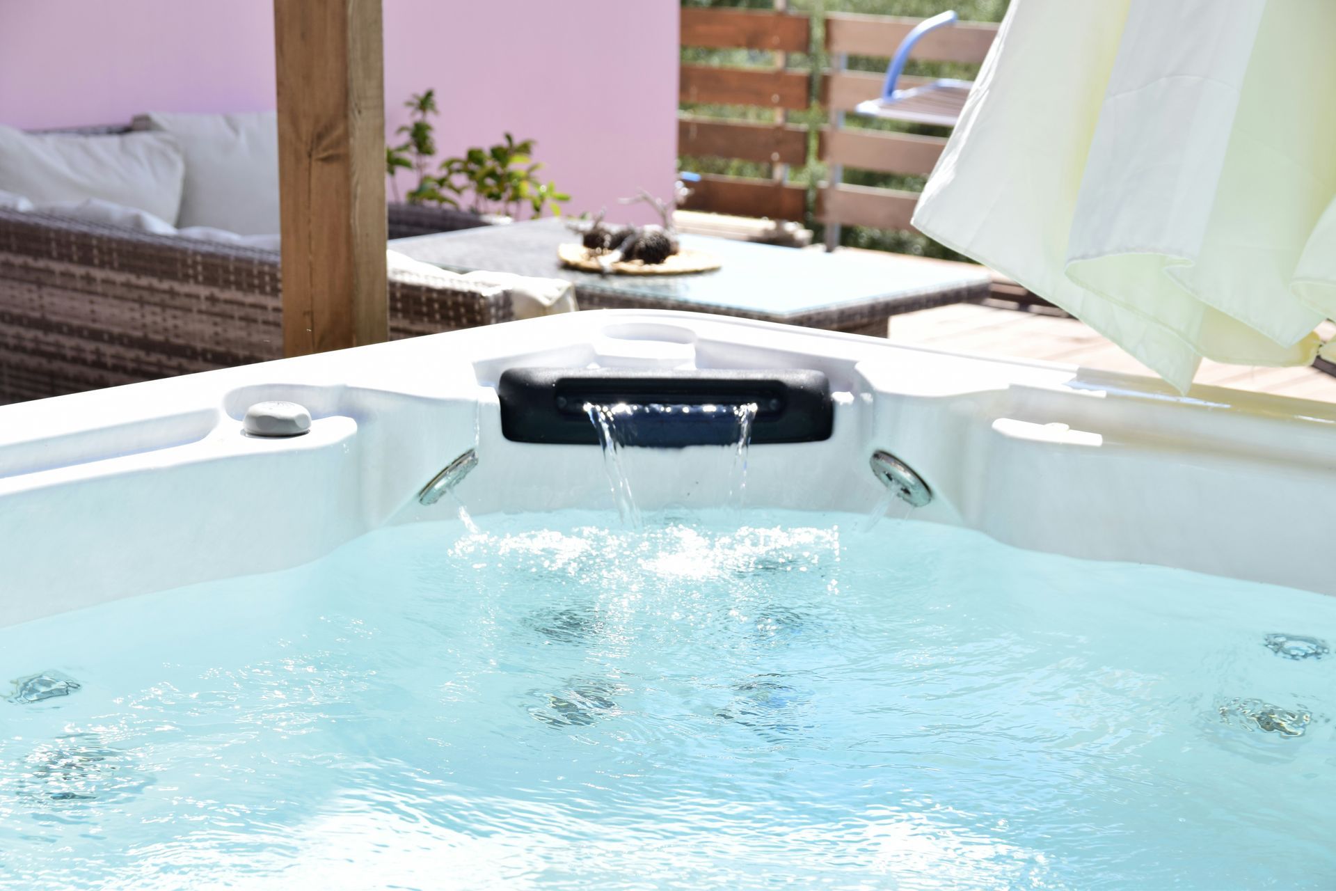 Backyard hot tub with bubbling blue water and a shaded patio lounge area