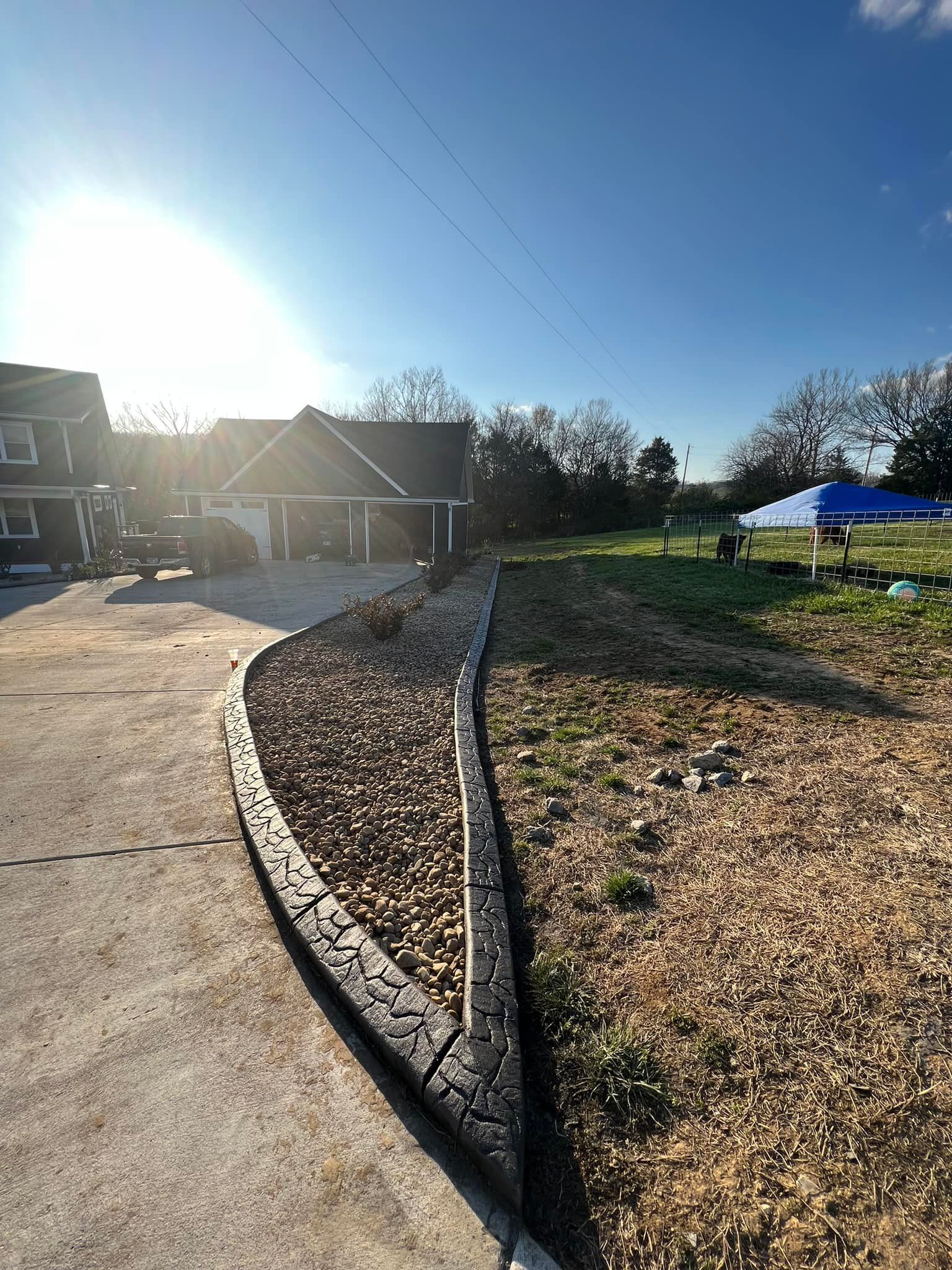 A concrete driveway leading to a house with a blue tent in the background.