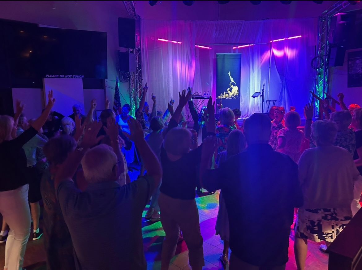 Crowded nightclub dance floor with raised hands under purple and blue stage lights