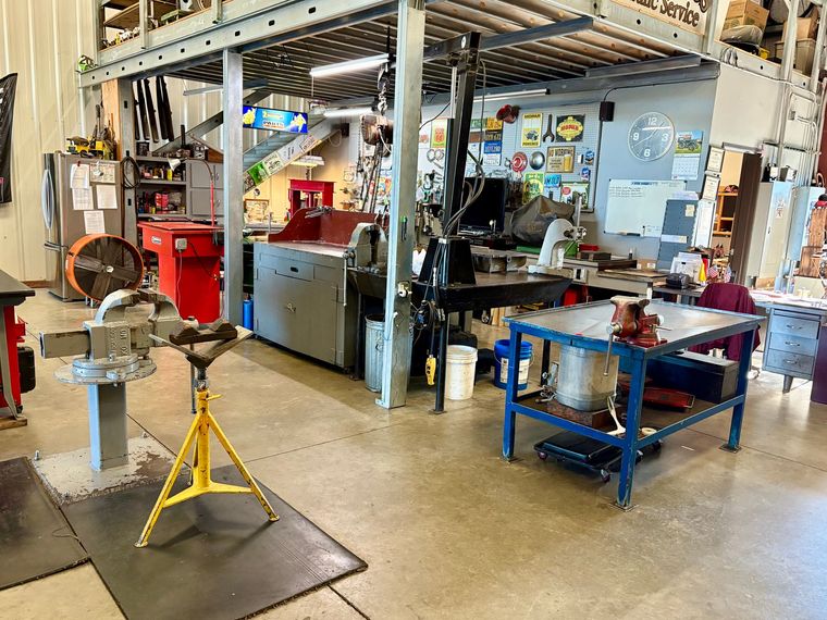 A technician in a hard hat checks equipment while inspecting blue industrial pumps in a mechanical room.