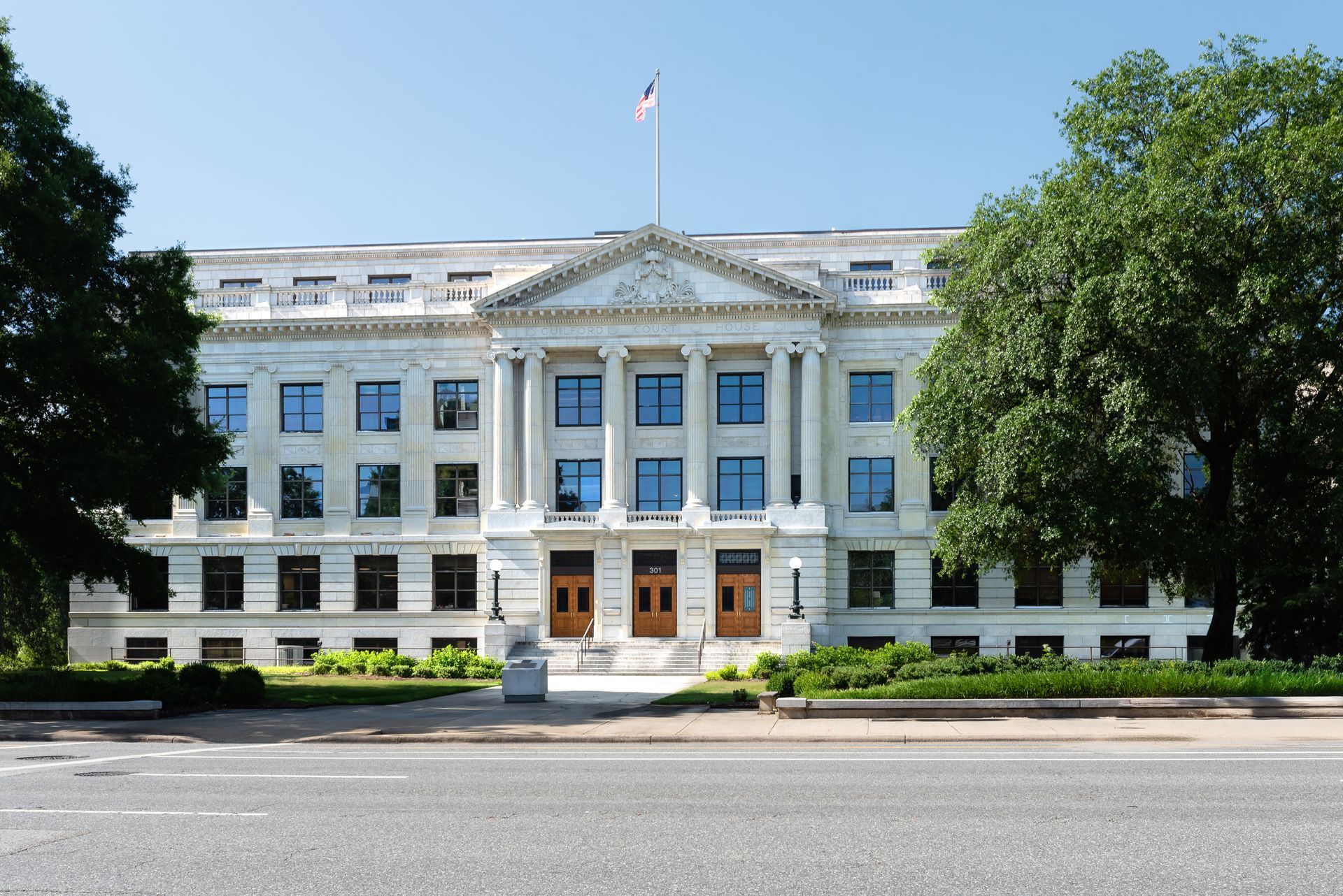 A large white building is surrounded by trees and grass