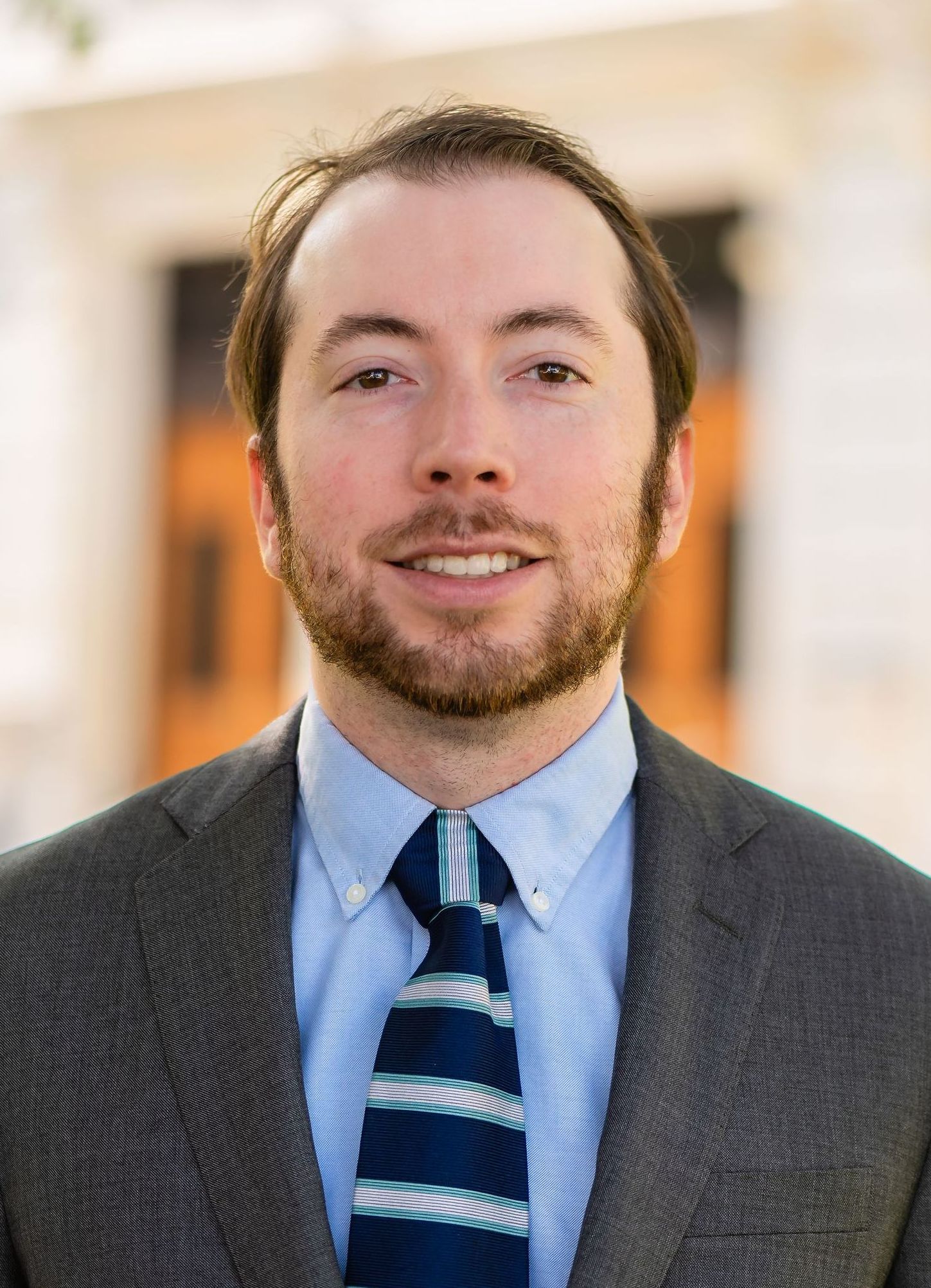 A man in a suit and tie is standing in front of a building.