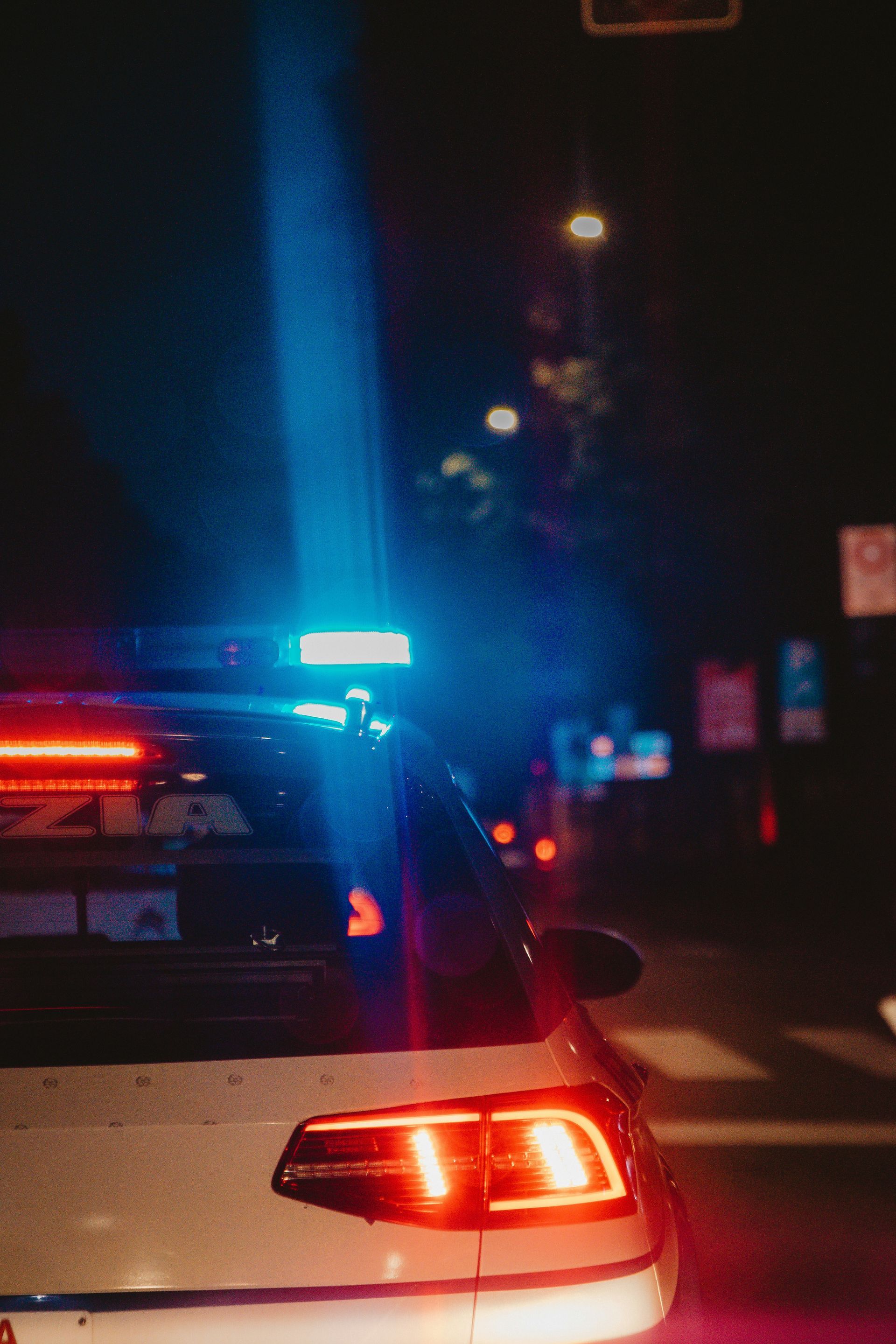 A police car is driving down a city street at night.