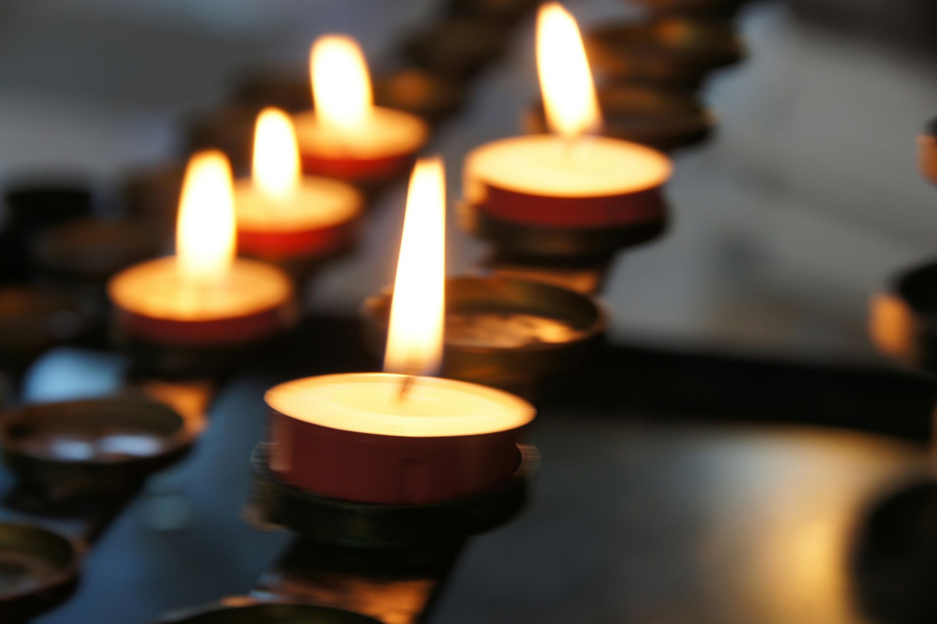 A row of lit candles are lined up on a table