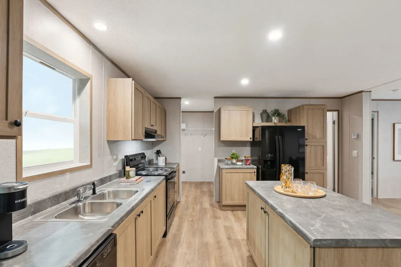Modern kitchen with light wood cabinets, gray countertops, and an island.