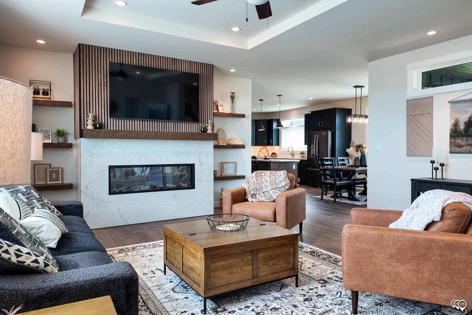 Living room with fireplace, TV, seating, and open view to kitchen and dining area.