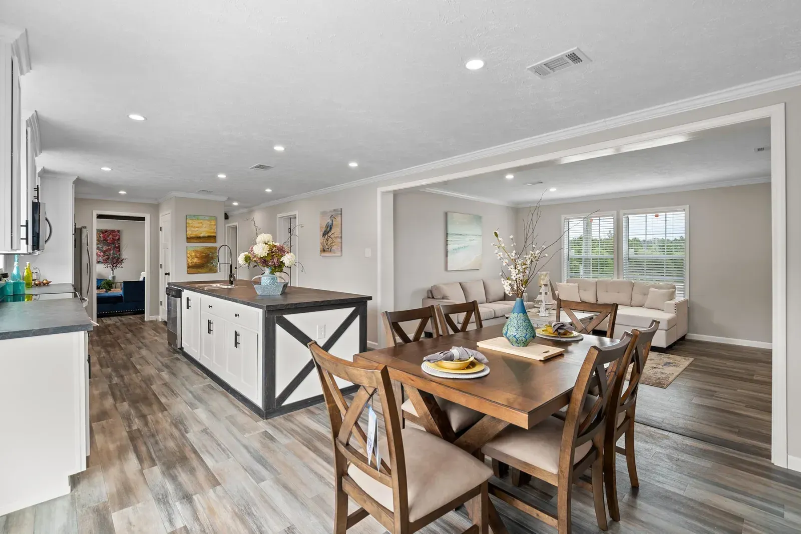 Open-concept kitchen and dining area with island, table, chairs, and living room visible. 