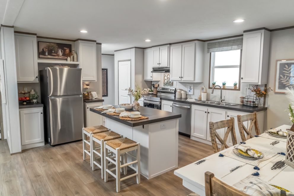 Modern kitchen with white cabinets, stainless steel appliances, and island with stools.