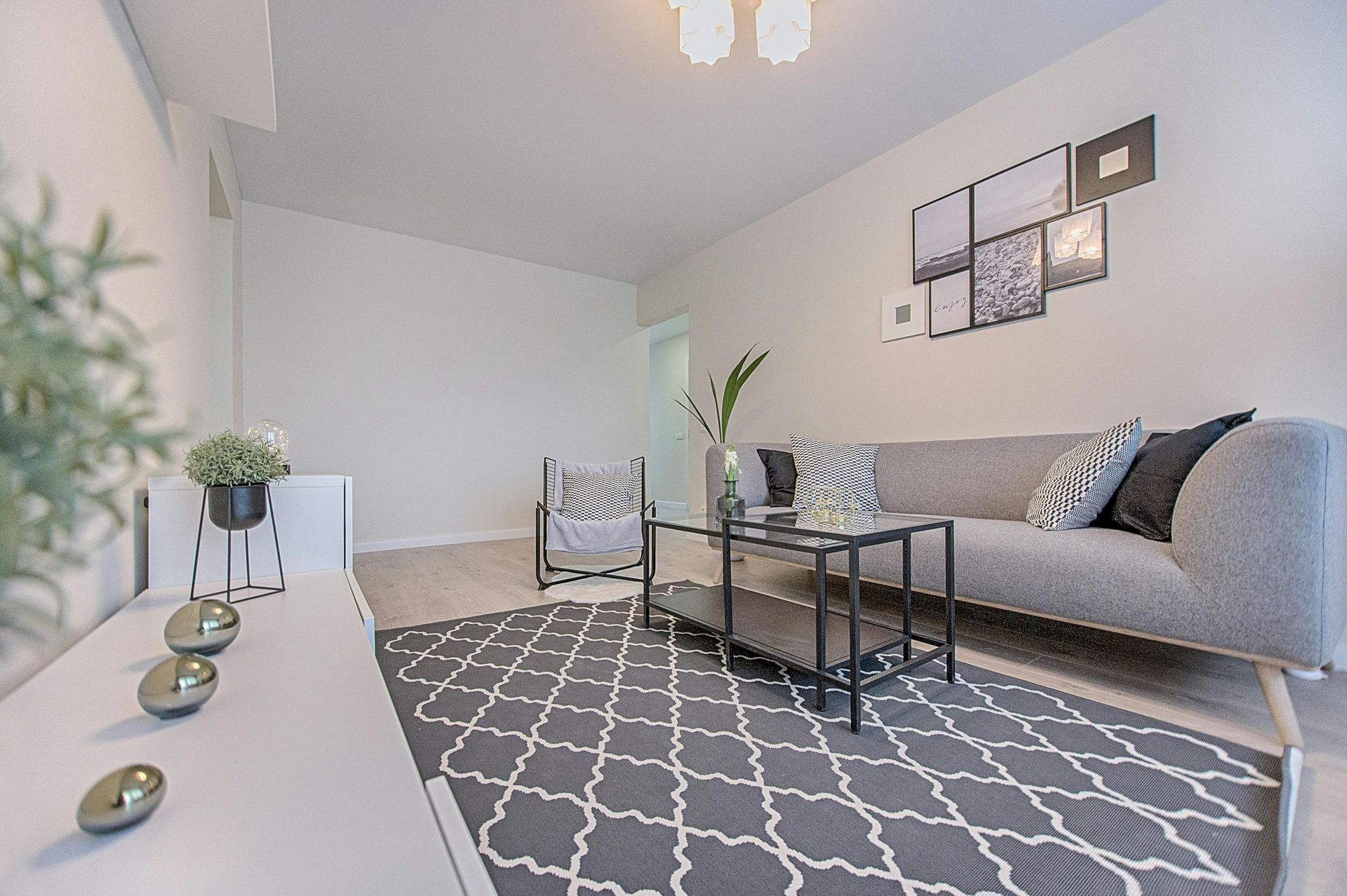 Modern living room with grey sofa, patterned rug, and wall art.