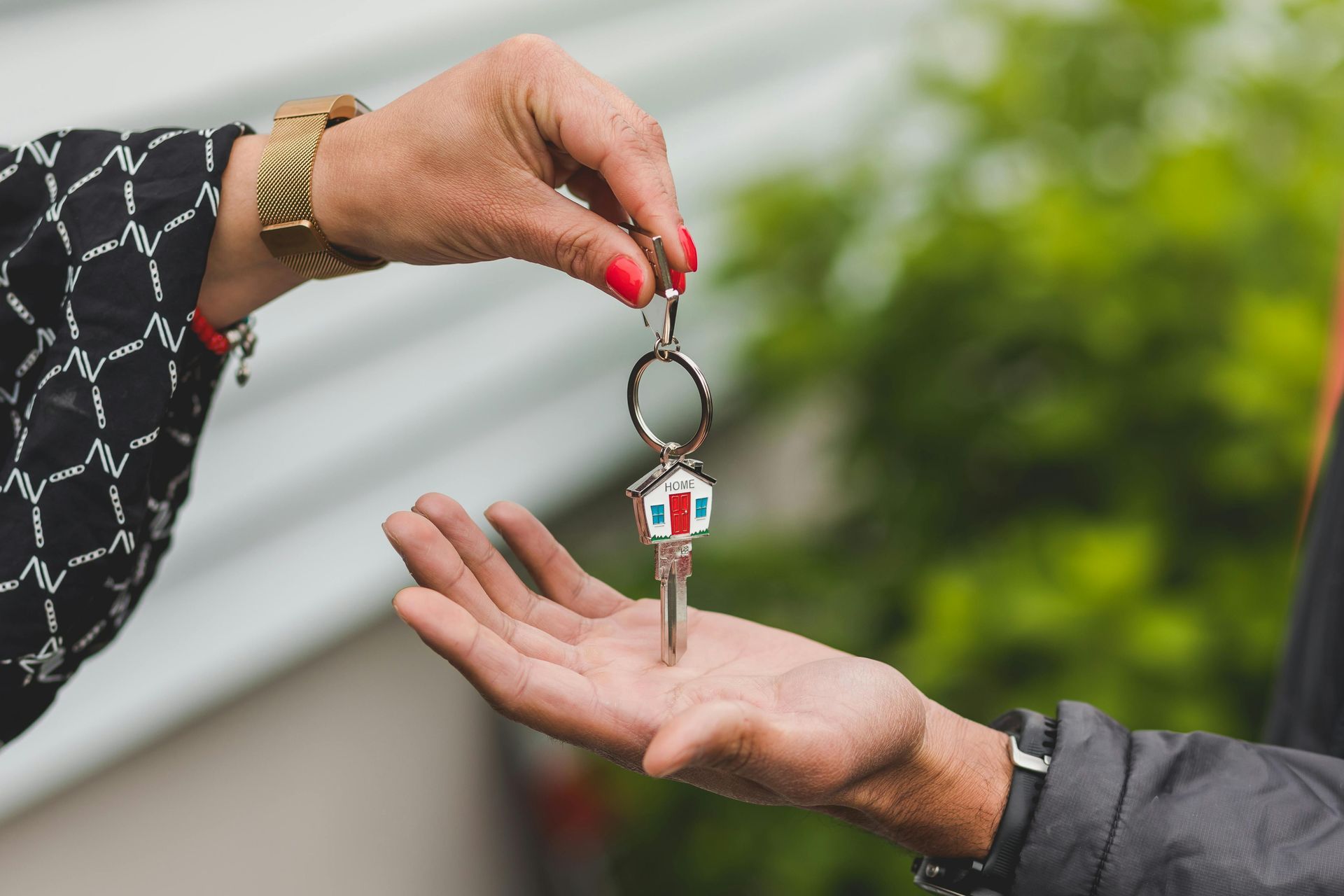 Hand passing house key to another hand.