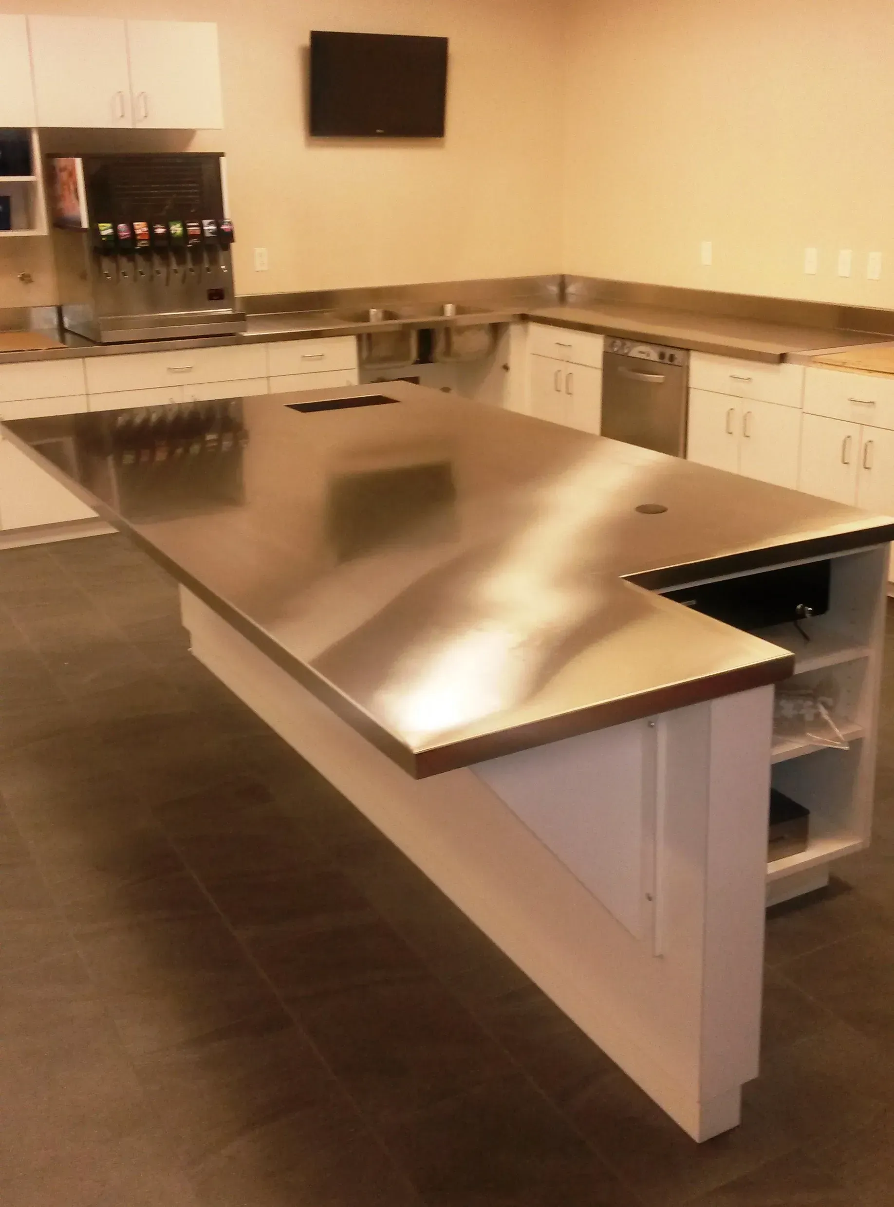 Modern kitchen with stainless steel island, white cabinets, dark floor, and built-in appliances