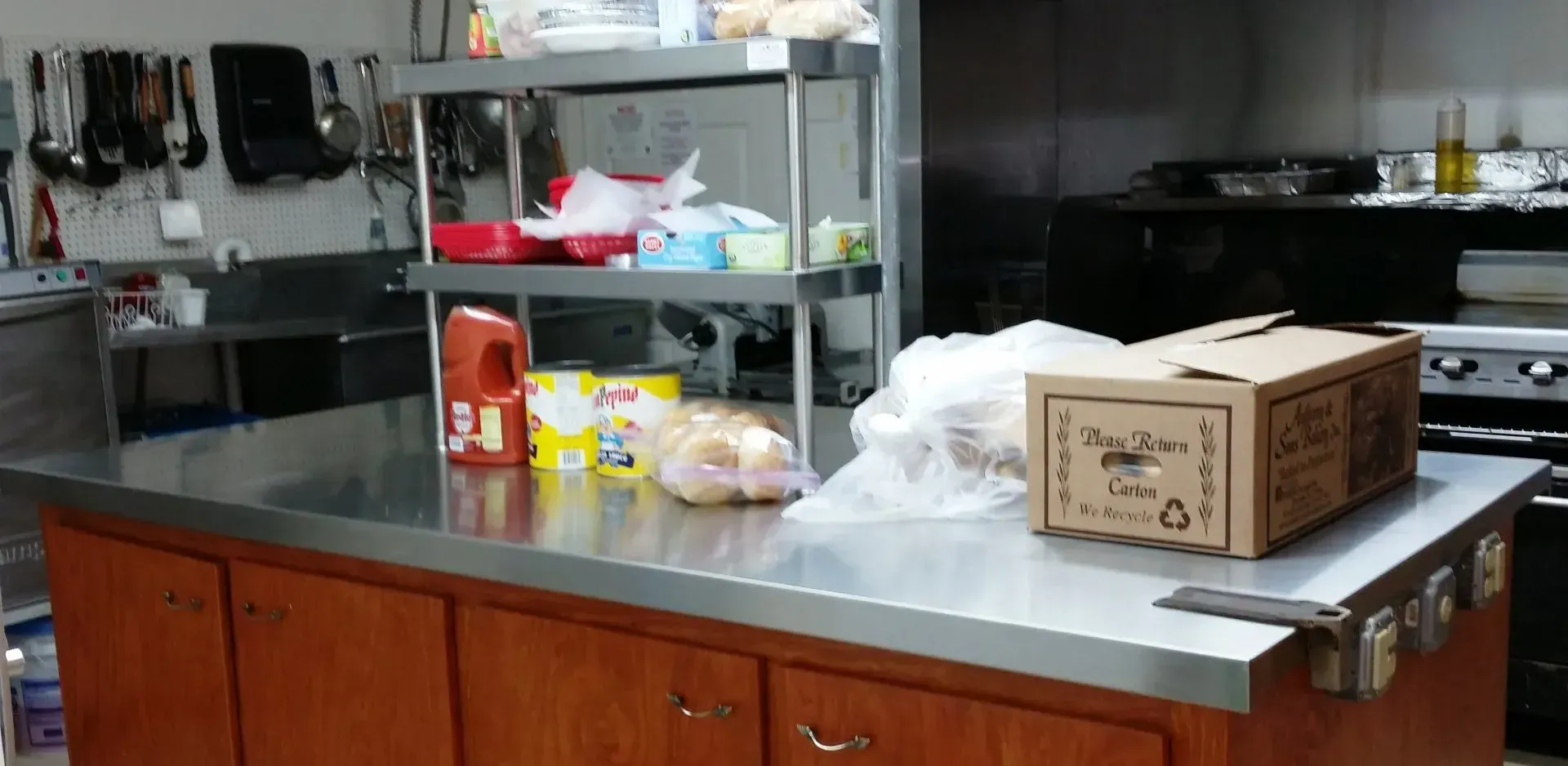Kitchen counter with stainless steel top, wooden cabinets, and several boxes and food items on it