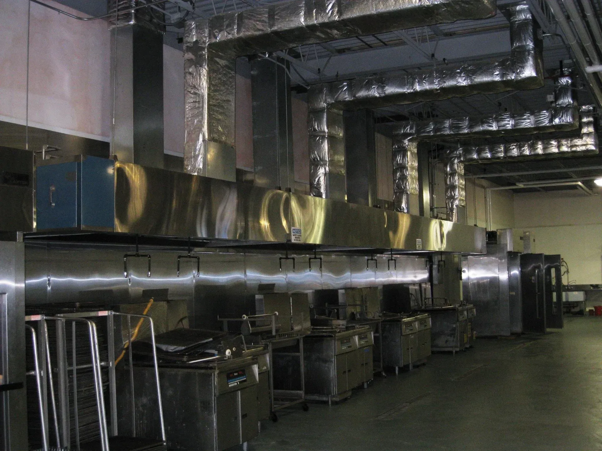 Industrial kitchen with large metal ventilation ducts and stainless steel equipment in a utility room
