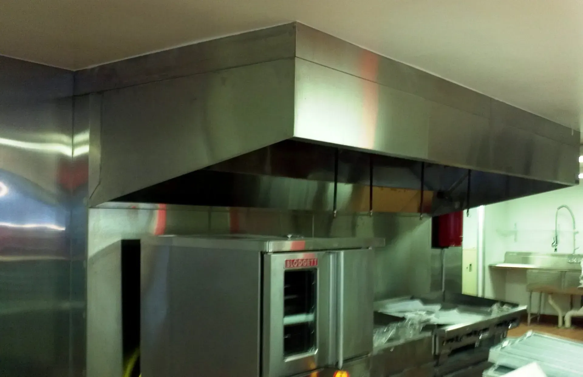 Industrial kitchen with stainless steel appliances and large ventilation hood