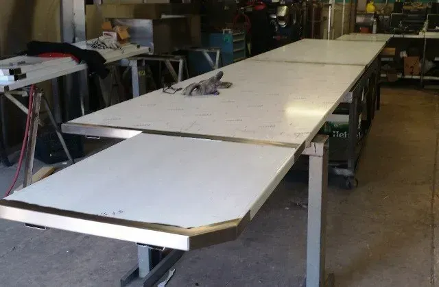 Long white folding tables arranged in a workshop or garage space