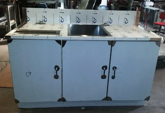 Three-door metal cabinet in an industrial kitchen or prep area, with stainless steel tops and sinks.
