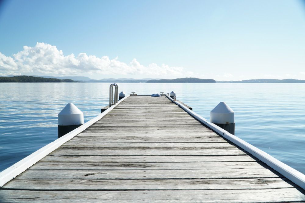 A Wooden Dock Leading Into a Body of Water — AAA Equipment Pty Ltd In Port Macquarie, NSW