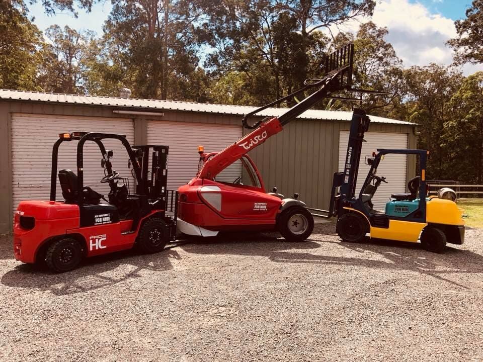 Two Forklifts Are Parked Next to Each Other in Front of A Building — AAA Equipment Pty Ltd In Taree, NSW