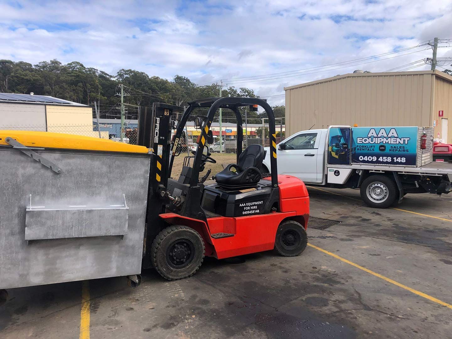 A Forklift Is Loading a Dumpster Into a Truck in A Parking Lot — AAA Equipment Pty Ltd In Redbank, NSW
