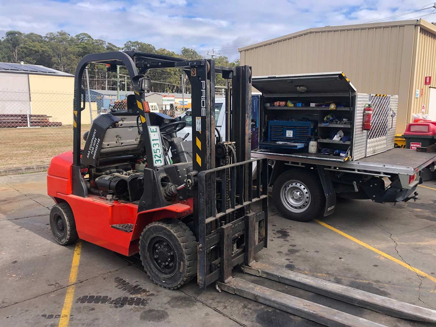A Red Forklift Is Parked Next to A Truck in A Parking Lot — AAA Equipment Pty Ltd In Redbank, NSW