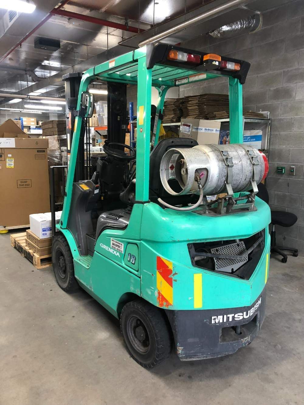 A Green Forklift with A Propane Tank on The Back Is Parked in A Warehouse — AAA Equipment Pty Ltd In Kempsey, NSW