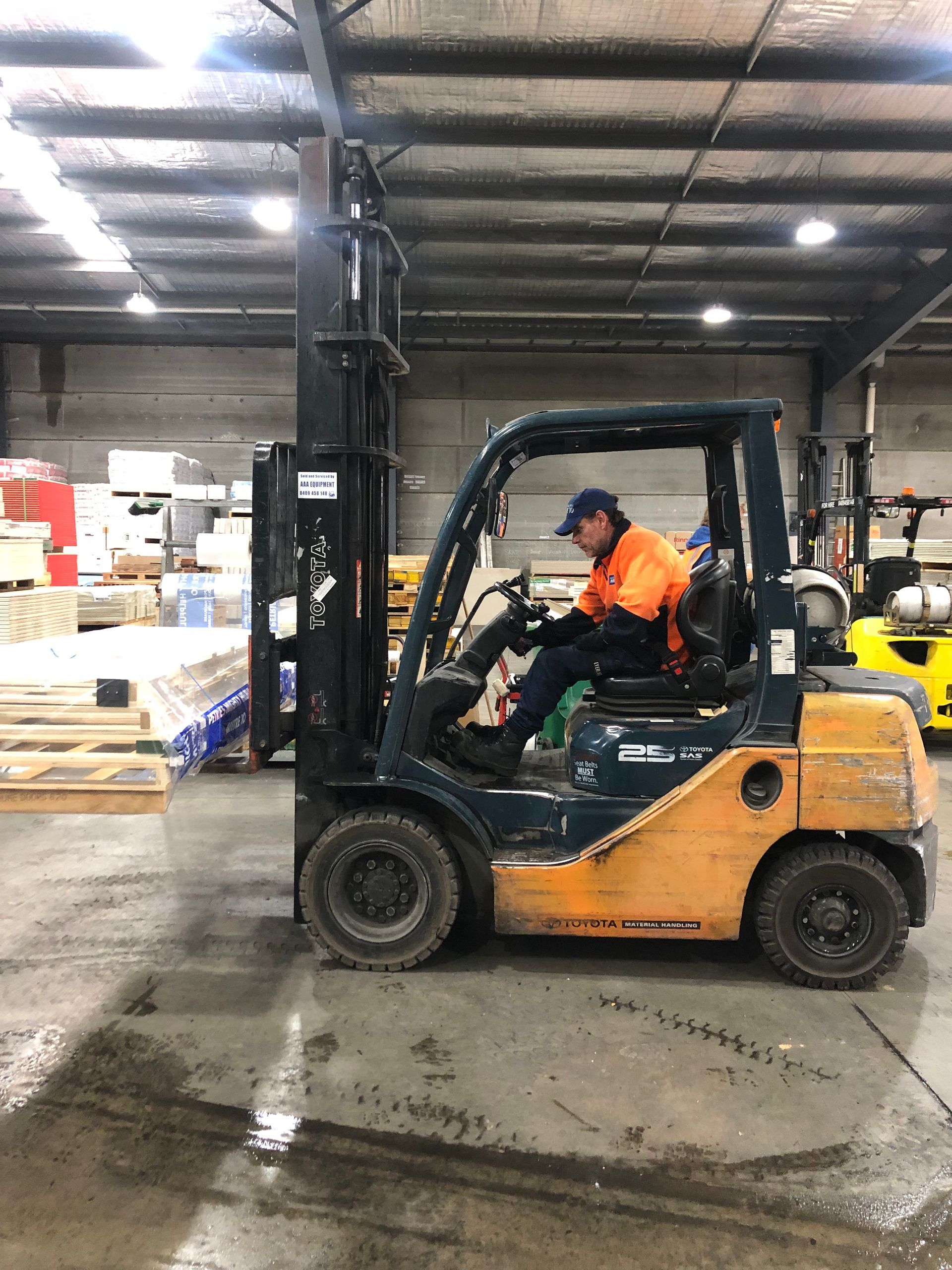 A man driving a Forklift in a large warehouse— AAA Equipment Pty Ltd In Redbank, NSW