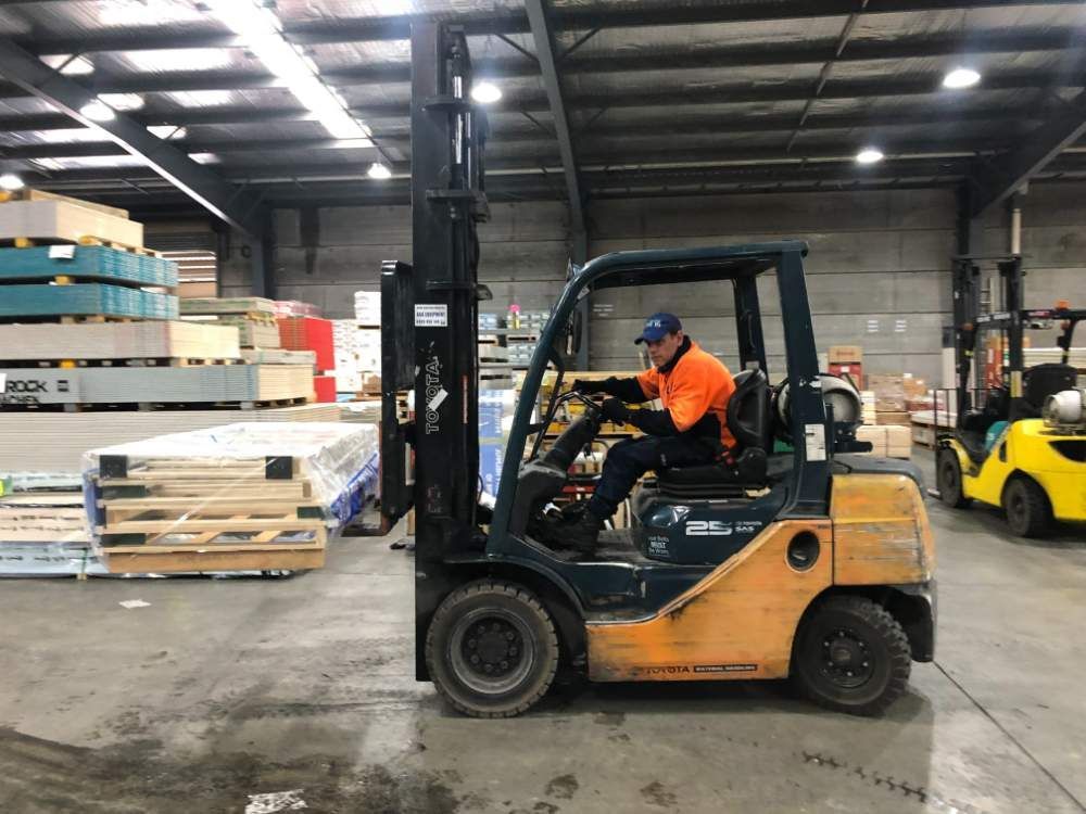 A Man Is Driving a Forklift in A Warehouse — AAA Equipment Pty Ltd In Kempsey, NSW