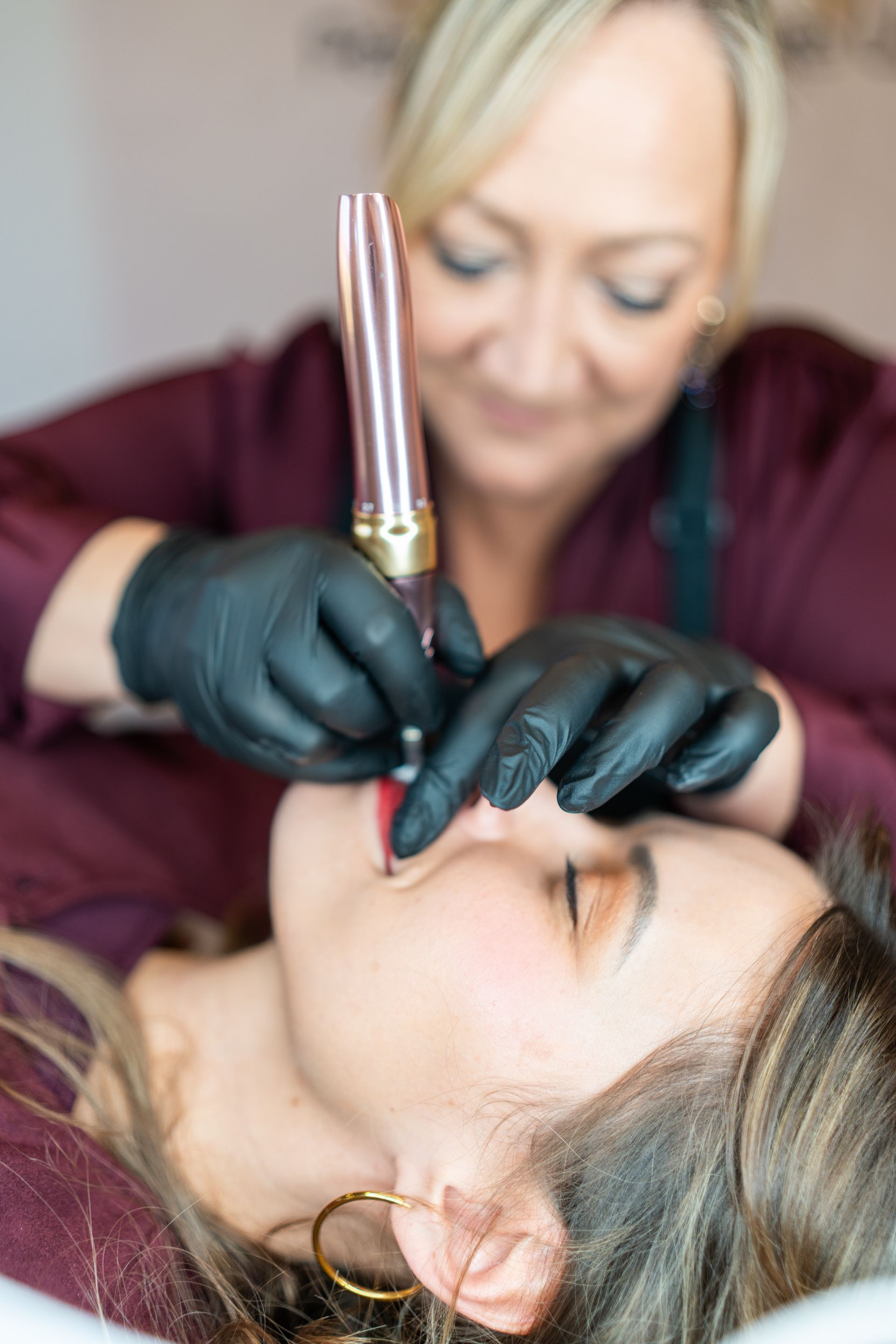 Person, die sich die Lippen tätowieren lässt. Techniker hält ein stiftähnliches Werkzeug an die Lippen.
