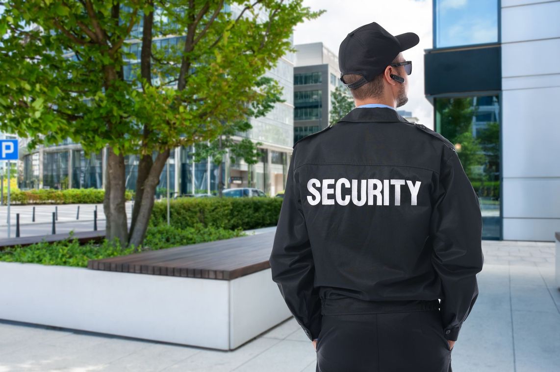 Security guard in black jacket standing outside a modern office building