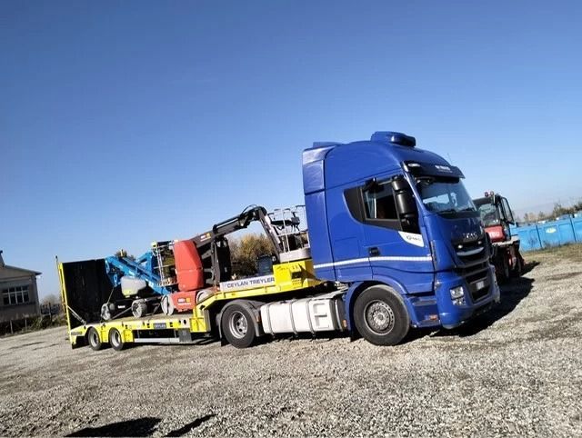 Un semirimorchio blu che trasporta attrezzature pesanti su un rimorchio