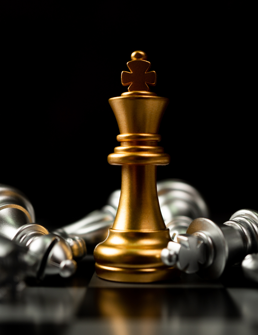 A gold chess king is standing in front of a pile of silver chess pieces on a chess board.