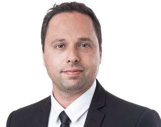 A man in a suit and tie is smiling for the camera