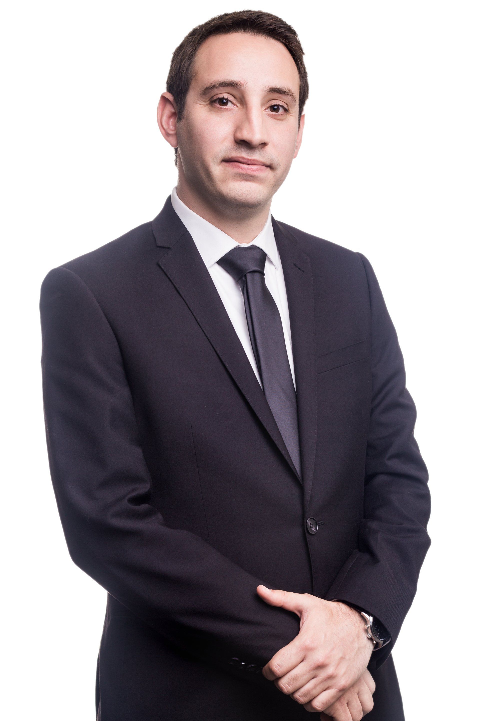 A man in a suit and tie is standing with his hands folded