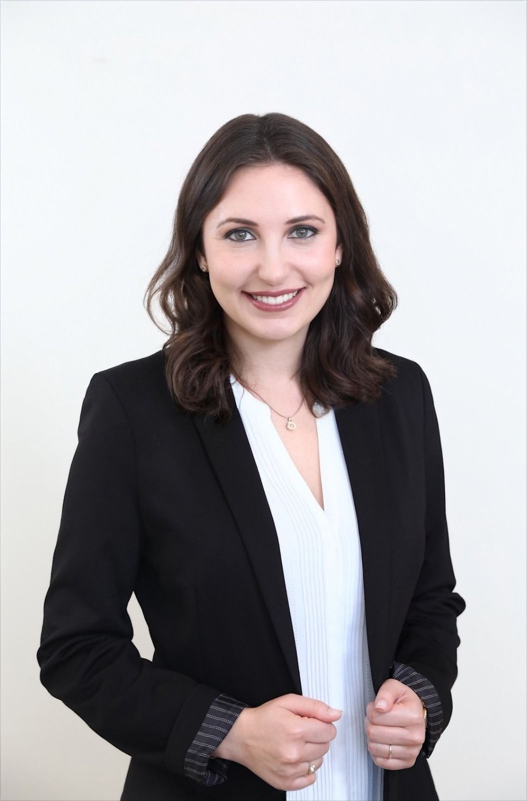 A woman is wearing a black jacket and a white shirt.