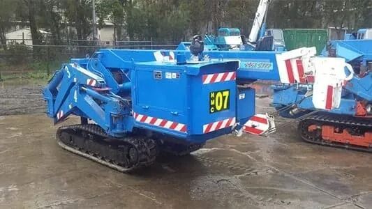 A Blue Crane is Parked in a Dirt Field Next to a Fence — Newcastle Cranes In Cardiff, NSW