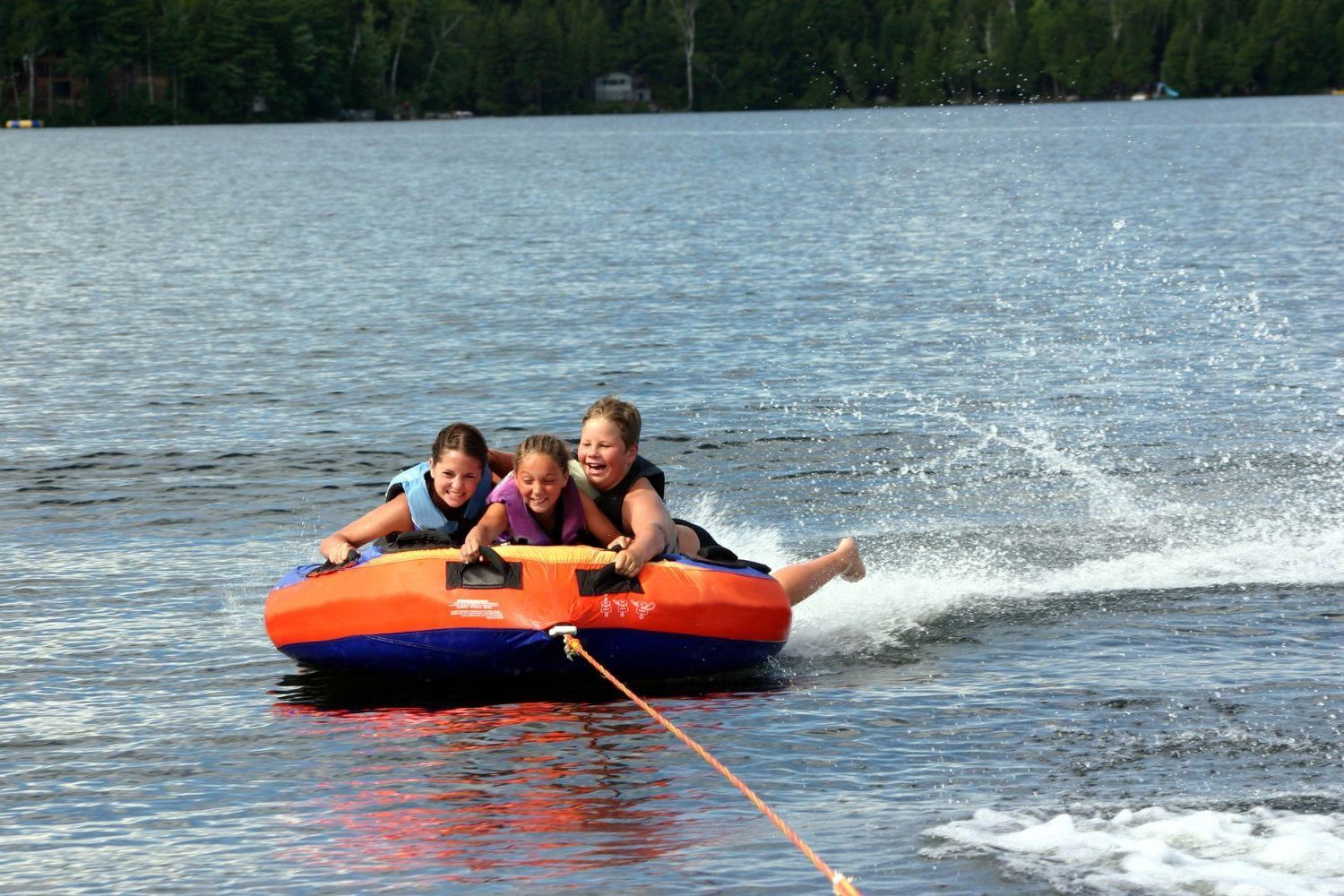A young girl is riding a tube in the water.