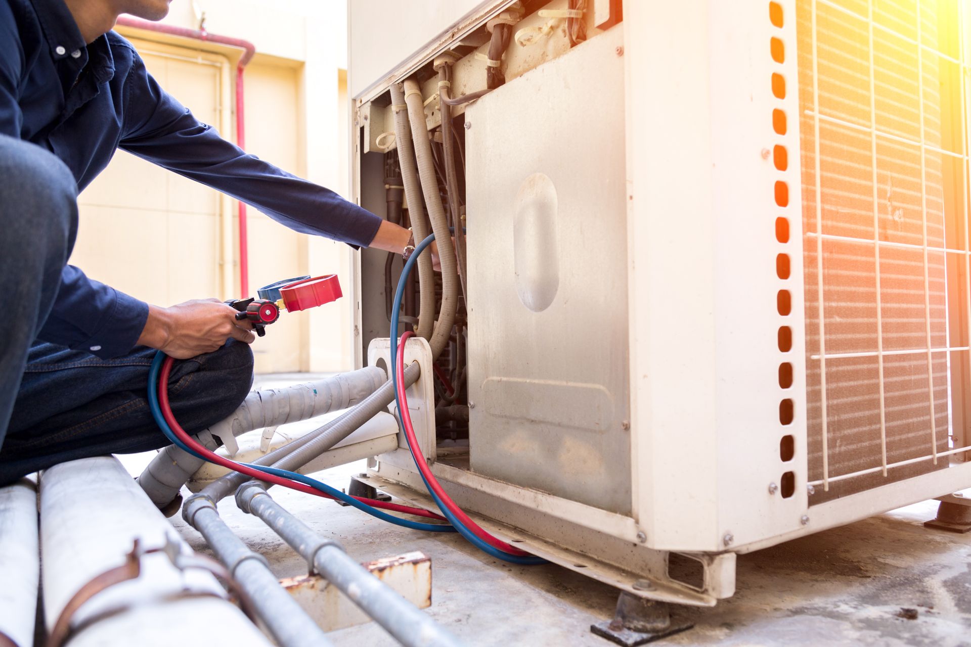 A man is working on an air conditioner with a hose.