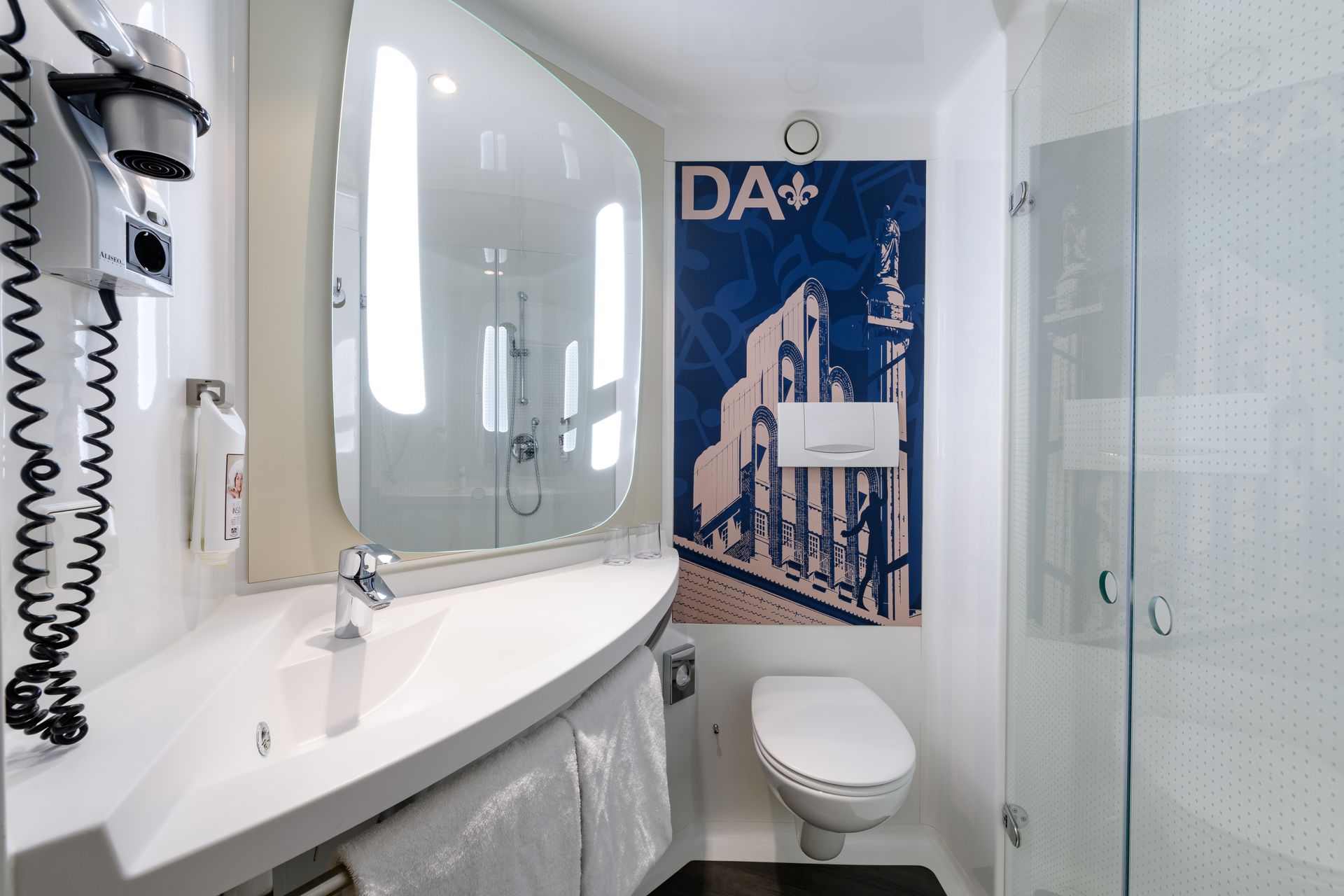 Barrierefreies Badezimmer mit Waschbecken, Spiegel, Toilette und blauem Duschvorhang in einem hellen, weißen Interieur