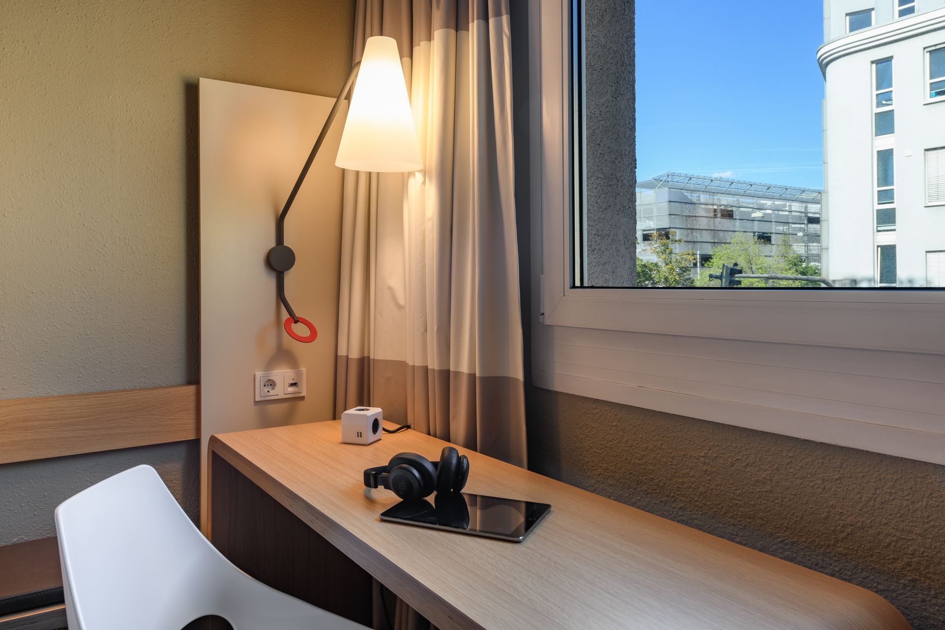 Hotelschalter mit Lampe, Stuhl und Kamera an einem Fenster mit Blick auf die Gebäude