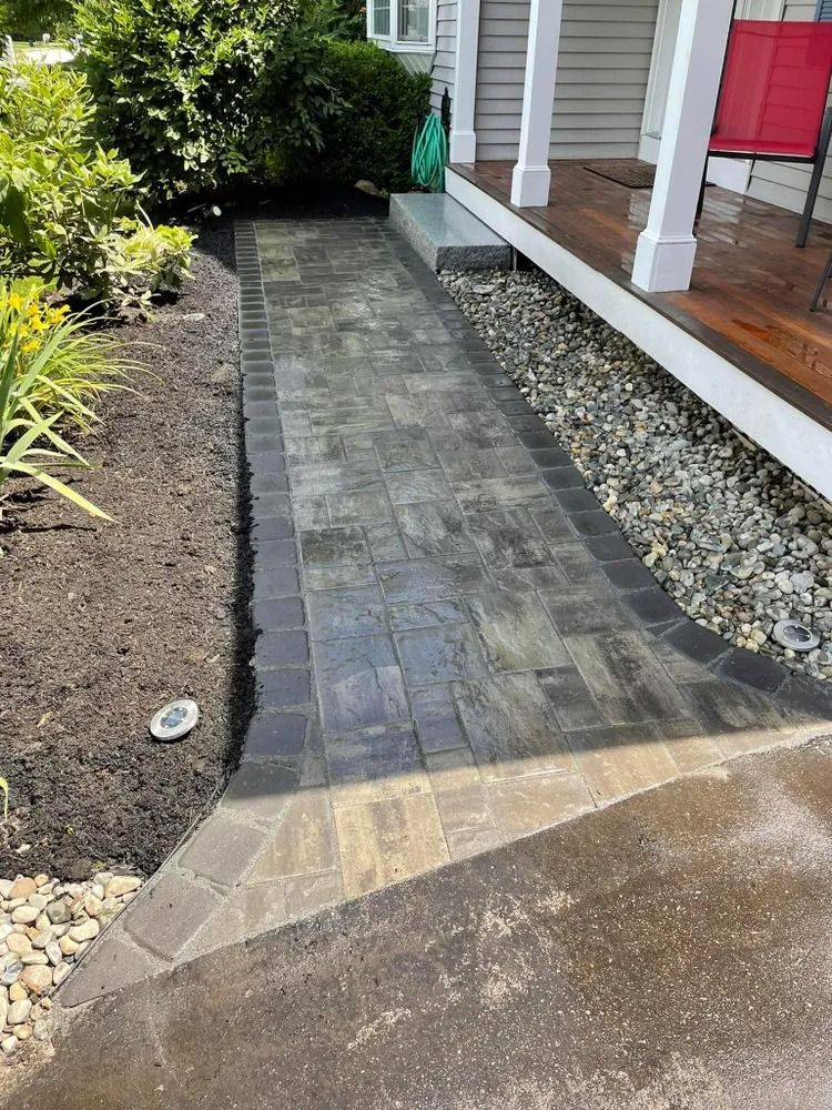 Paver walkway to porch with dark border, edged by mulch on left and gravel on right.