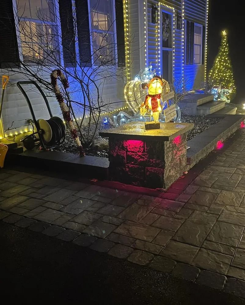 A house decorated for the holidays, with colorful lights, a snowman, and a candy cane in front.