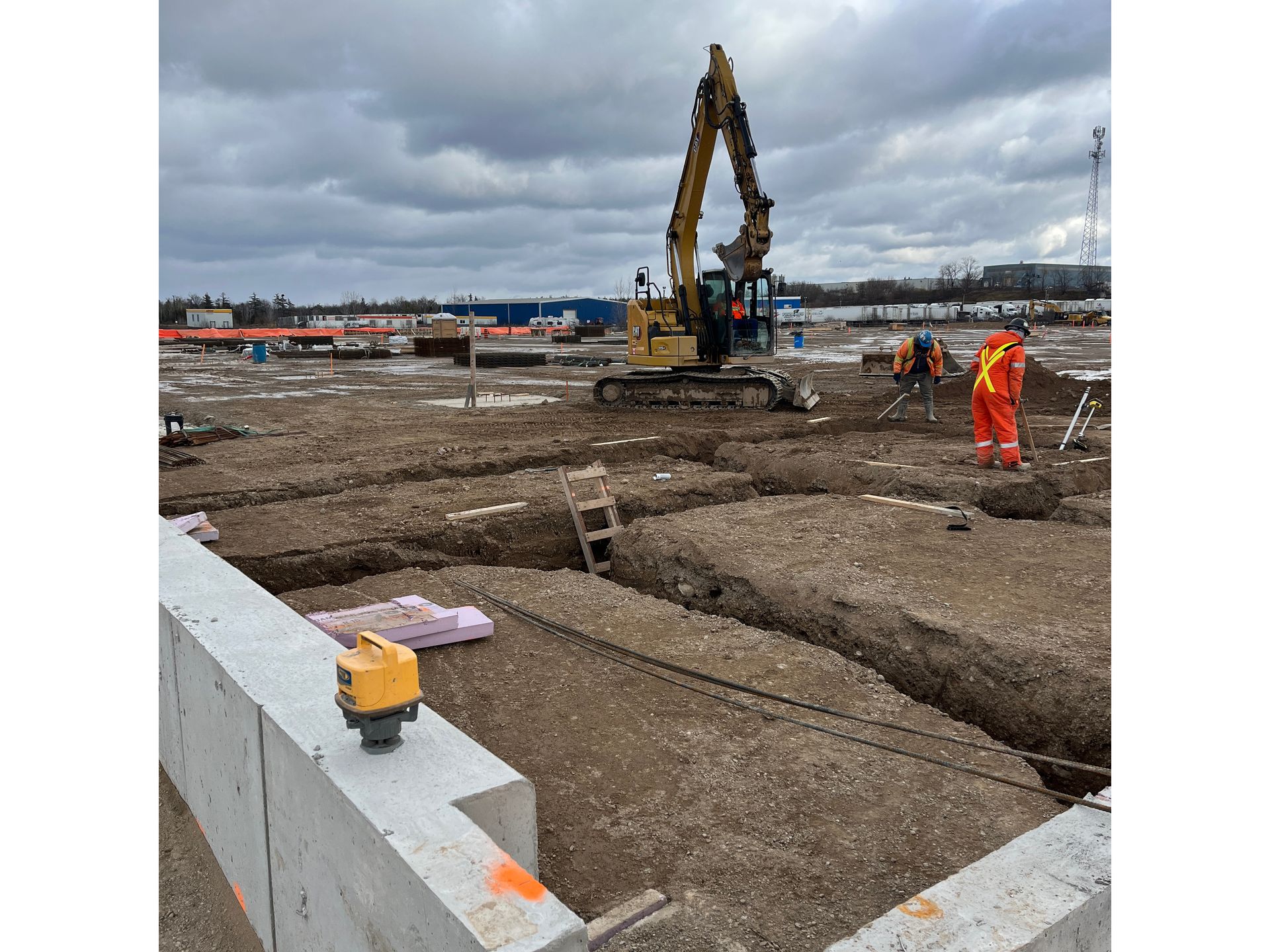 A construction site with a bulldozer and a laser level in the foreground.