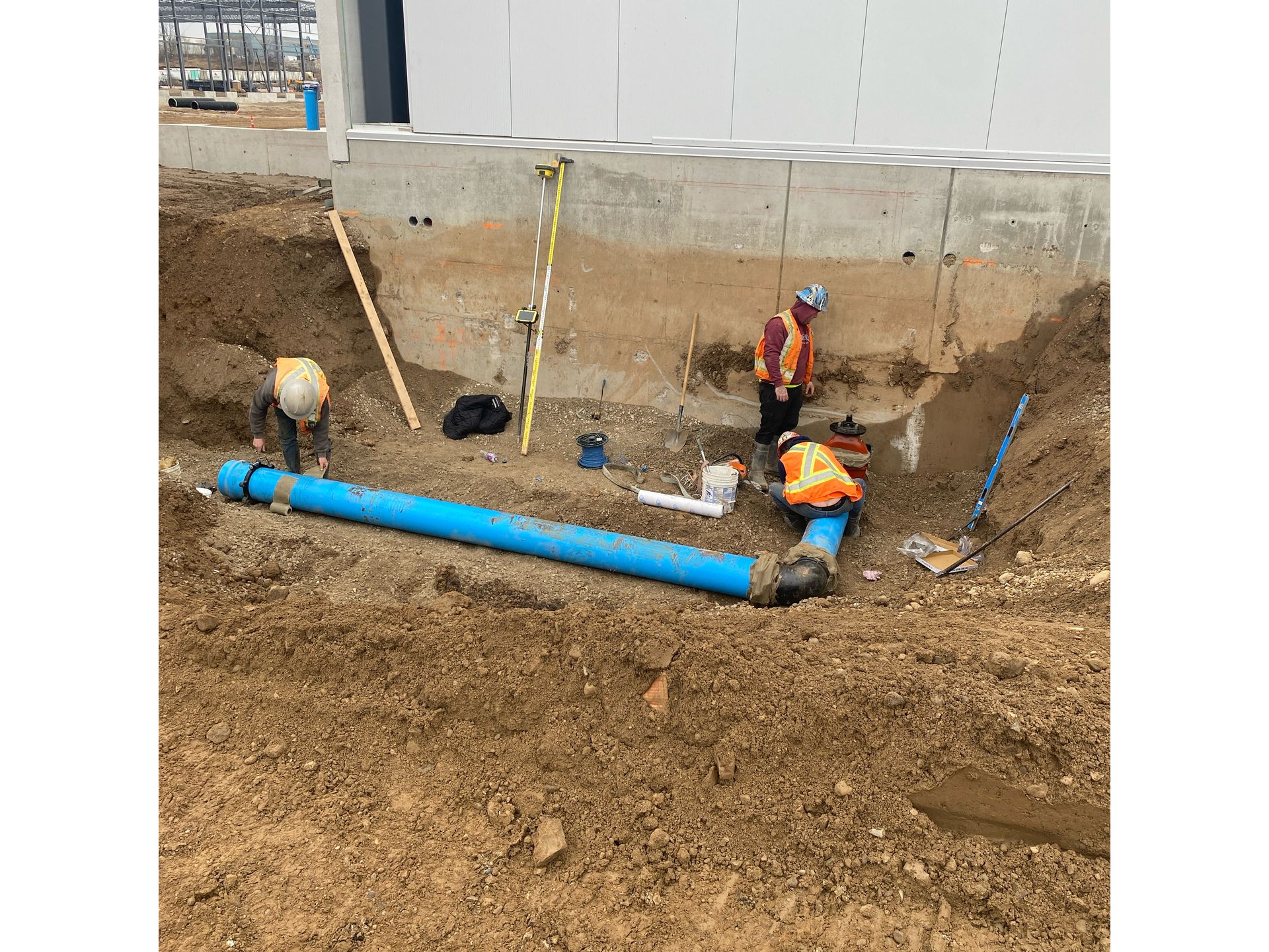A group of construction workers are working on a pipe in the dirt.