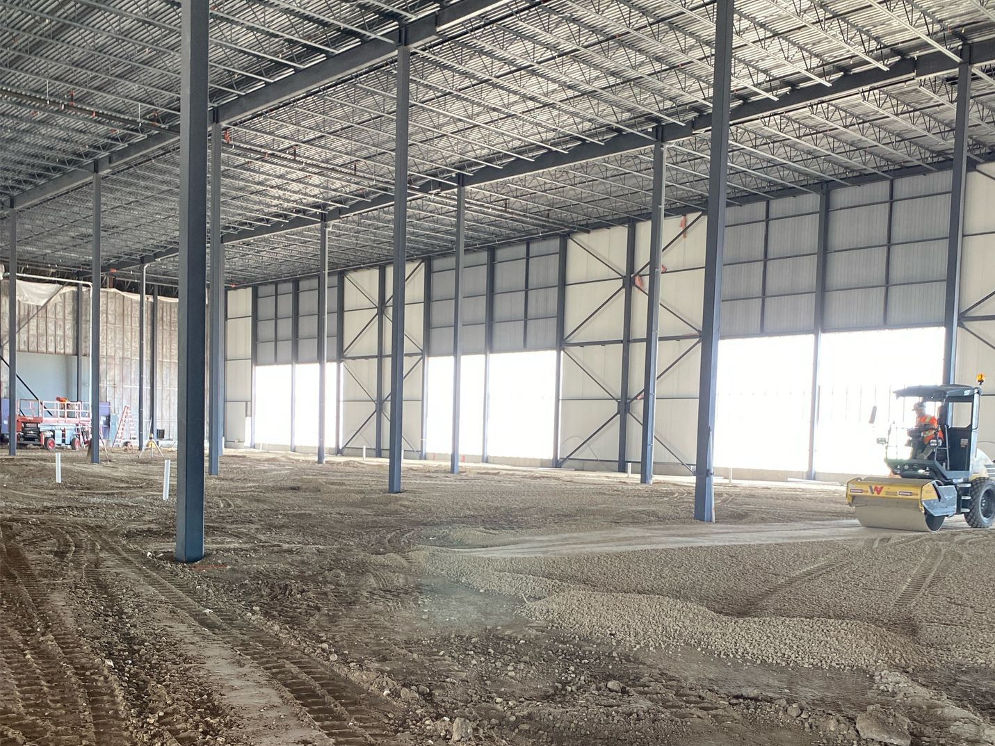A large warehouse under construction with a bulldozer in the middle of it.