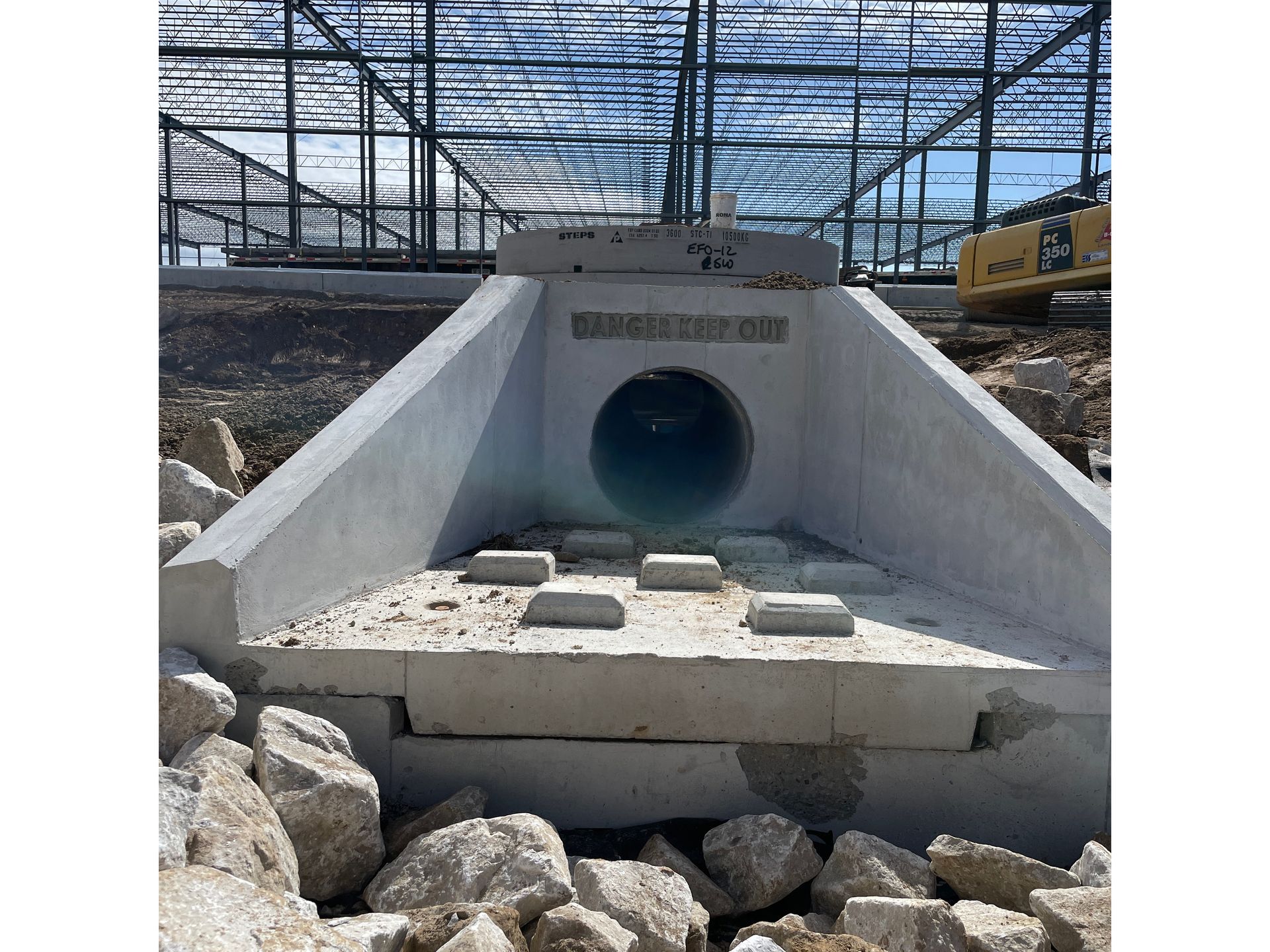 A large concrete pipe is being built in a construction site.