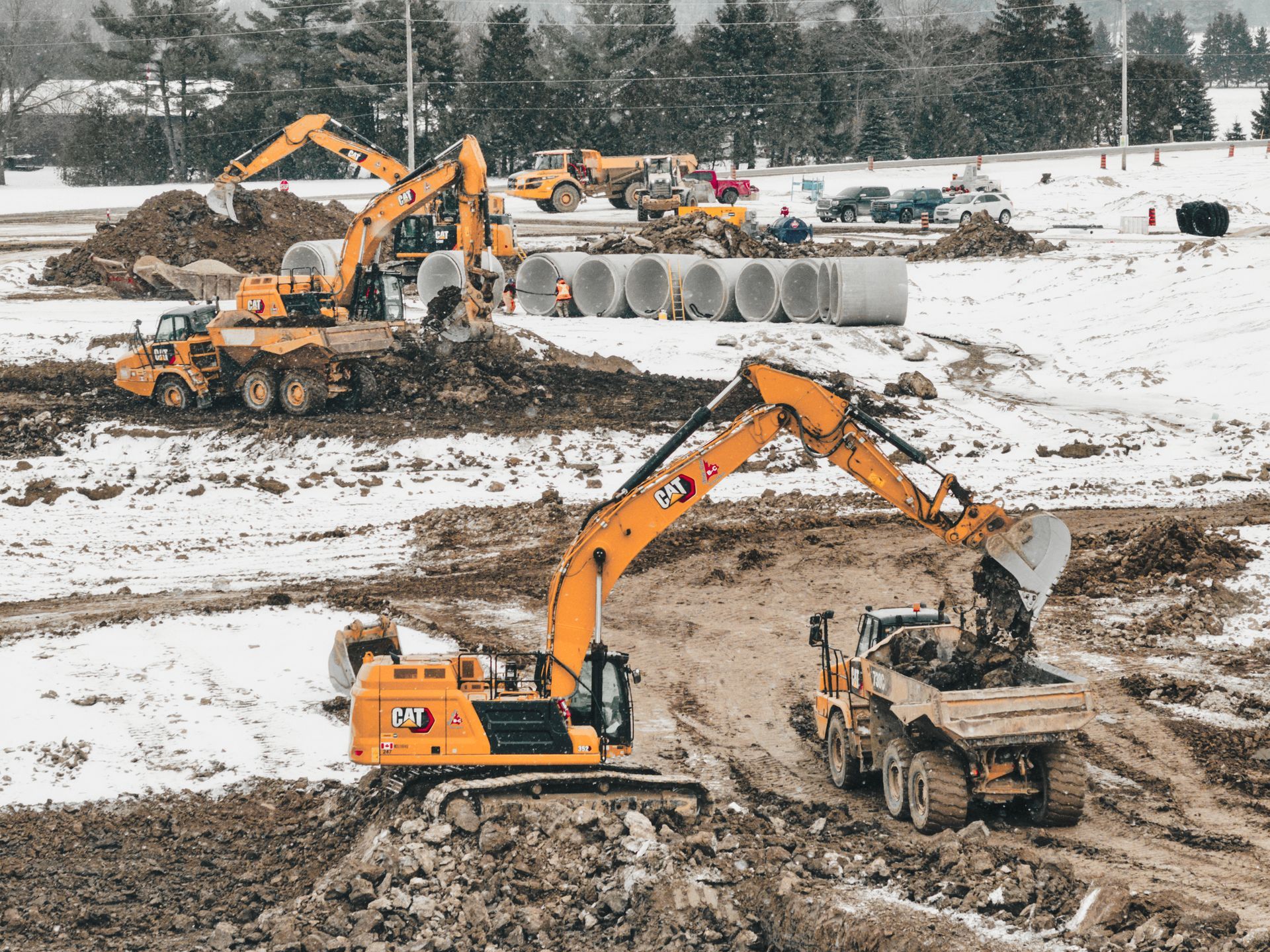 A group of construction vehicles are working on a construction site in the snow in St. Thomas
