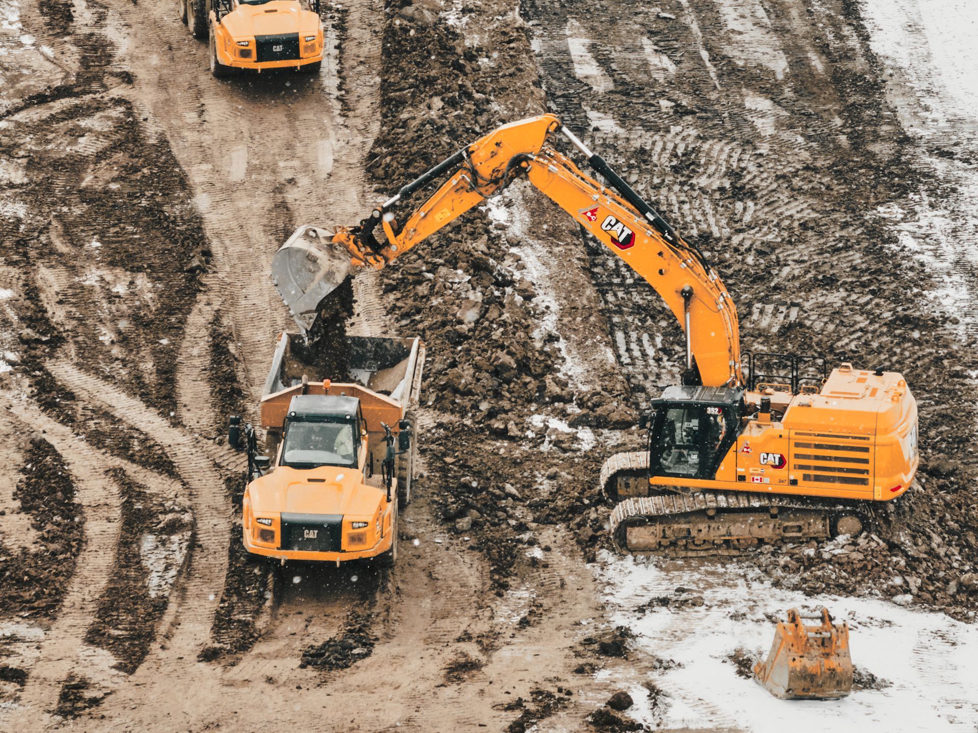 A group of construction vehicles are working on a dirt road in St. Thomas